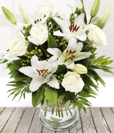Forever in my thoughts - This elegant mix of white blooms is sure to charm them. Exquisite white roses blend beautifully with lush lilies, green hypericum, and seasonal foliage.
