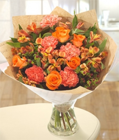 Sunset - Delicate orange Carnations sit perfectly along side the beautiful fragrant Rose and Alstoemeria blooms. Sprigs of red Hypericum complete this pretty bouquet.