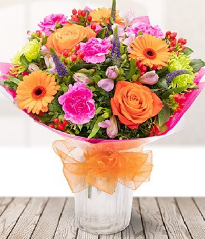Sunrise - A glorious mix of orange blooms with bursts of pink, purple and green stems make up our beautiful Sunrise bouquet. A mix of roses, germini, alstro's, carnations, and other seasonal blooms and foliage are delicately arranged to create this bouquet.