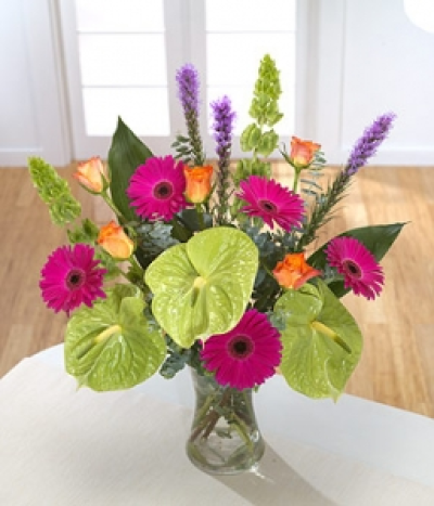 Kaleidoscope Bouquet - A contemporary mix of hot pink Gerbera and green Anthurium star in this tropical design. Purple Liatris and orange Roses bring warmth, while Aspidistra and Molucella form an elegant structure. Hand-Tie in water.