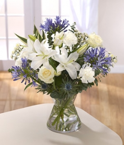 Blue Ice - This appealing bouquet features white Lilies, Roses and Chrysanthemums, highlighted with blue Agapanthus and Eryngium. Hand-Tie in water.
