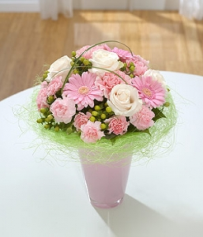Pink Perfection - A compact vase arrangement of pale pink Roses, Germini, spray Carnations and green Hypericum sitting on a delicate green sisal collar.