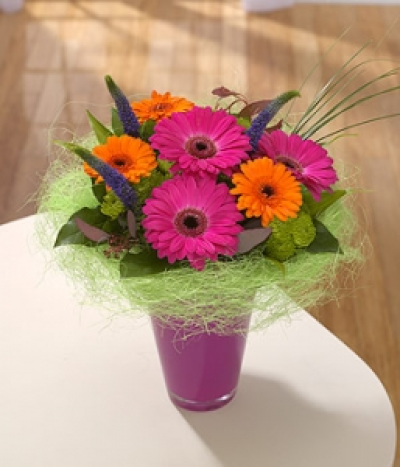 Turkish Delight - This contemporary design is bursting with vibrant orange and pink Gerbera and framed with a zesty lime green collar. Blue Veronica and Bear Grass add distinction to this elegant arrangement.
