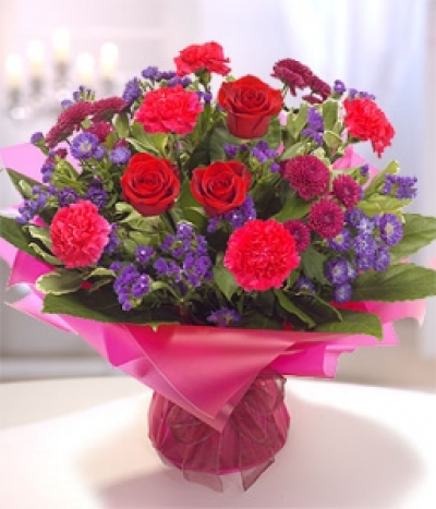 Pure Passion - Aqua pack hand-tied bouquet delivered in water for freshness. Passionate, rich colours of red, purple and cerise. Containing a red Rose, Carnations, Chrysanthemum, Monte Cassino and Statice.