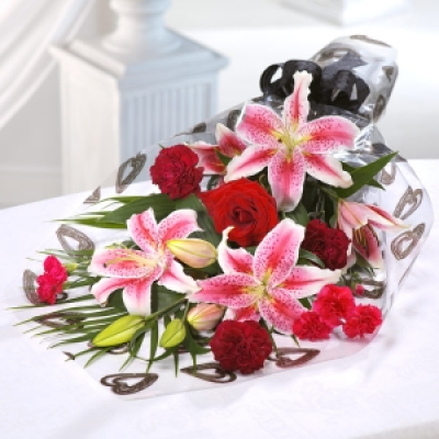 Kiss Me - Striking pink Lilies, mixed with deep red Roses and Carnations a generous bouquet.