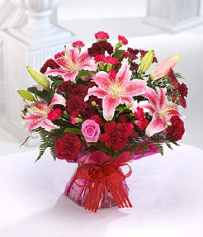 My Star - A sumptuous selection of flowers in rich reds, burgundy and pinks, featuring Lilies, Roses and Carnations, beautifully presented in a hand-tied for the perfect gift. Hand-Tie in water.