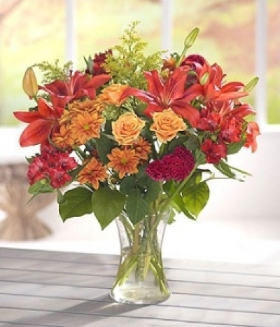 Peach Embers - A rust red colour combination of Lilies, Roses and Chrysanthemums with a touch of Solidaster creates a glowing bouquet. Hand-Tie in water.