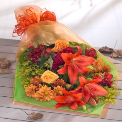 Jupiter - A rust red colour combination of Lilies, Roses and Chrysanthemums with a touch of Solidaster creates a glowing bouquet.