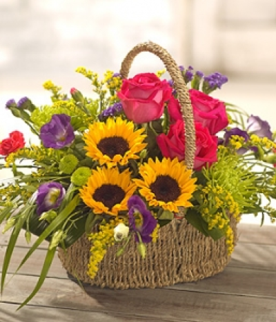 Hotter than July - A colourful, sunshine basket arrangement containing bright Sunflowers and hot pink scented Roses. A simply stunning, fuss free flower arrangement. Just add water occasionally.