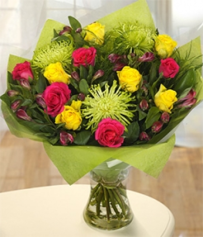 Anastasia - A sumptuous arrangement of yellow and cerise Roses expertly combined with the zingy green forms of Anastasia and cerise Asltromeria. Ruscus leaves complete the display. Hand-Tie in water.