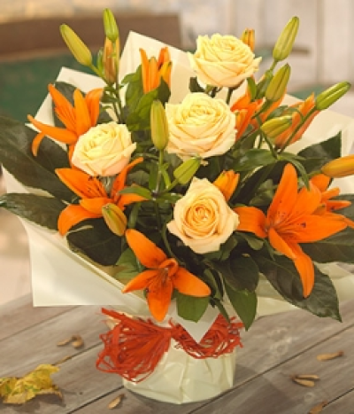 Autumn Rose & Lily - Warm orange Lilies and pretty peach Roses perfectly combined to form this gorgeous aqua packed flower arrangement.