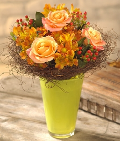 Golden Glow - A glorious golden glow of peach Roses, orange Chrysanthemums, Alstromeria and Hypericum berries perfectly combined and presented in a luscious lime green glass vase.