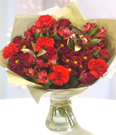 Fireside - Fiery red Carnations and deep red Chrysanthemums have been perfectly married with rich red Roses. Red Alstroemeria and a touch of gold Ruscus complete this stunning bouquet.