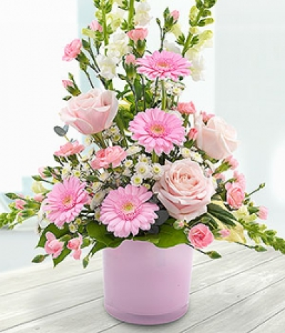Cascade - Pink Roses, Germinis and Carnations with delicate white Antirrhinums and Spray Chrysanthemums in a pretty pink glass vase.