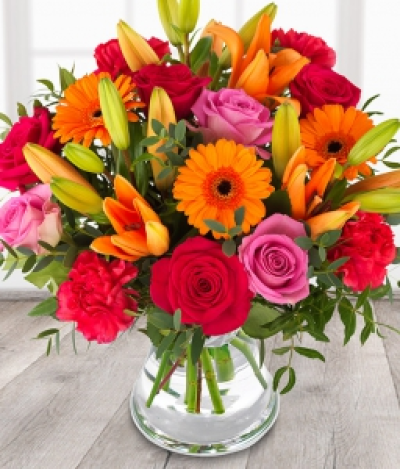 Fruit Salad - Send your love with this vibrant bouquet of the finest and freshest cerise roses, red roses, orange germini and orange lilies topped with eucalyptus.