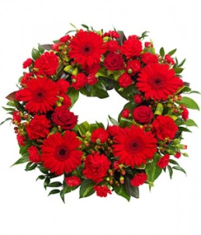 Red Wreath - A bright red wreath featuring Roses, Gerbera and Carnations with a mix of lusciuous green foliage.
