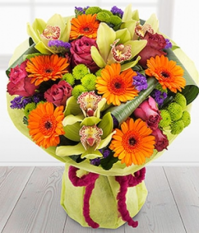Masquerade - Green Cymbidium Orchids are nestled in amongst cerise Roses, orange Germini, purple Satis and green Spray Chrysanthemums. An absolutely stunning display thatâ€™s bursting with colour.