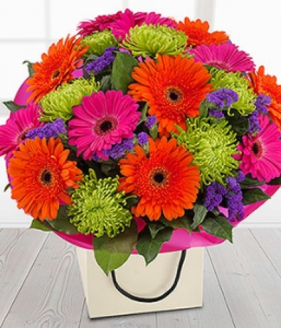 Happy Days - A bright and dramatic flower gift bag bouquet. Cerise and orange Gerberas married with deep purple Statis and glorious green Chrysanthemums. If you're going for WOW this is the bouquet for you.