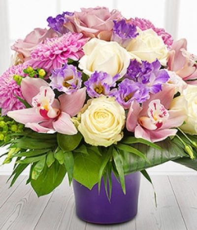 Tropical Splash - Add a touch of the tropics with this absolutely stunning flower arrangement. Pink Orchids, Roses and Dahlias with cream Roses, purple Lisianthus and gorgeous green Hypericum Berries in a purple ceramic pot.