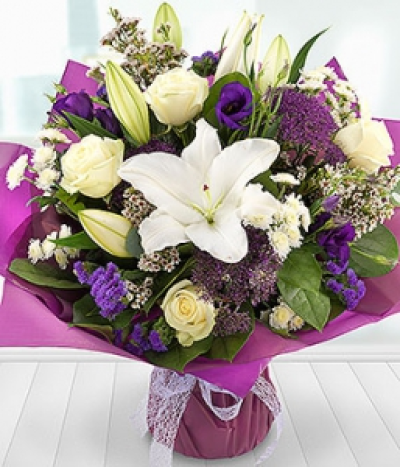 Tapestry - A sophisticated arrangement of crisp, white Lilies, Roses and Wax Flowers married with simply sumptuous purple Lisianthus and Statis blooms, finished with a dash of Eucalyptus and Salal.