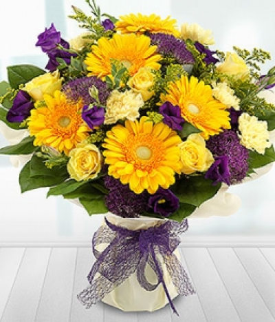Rise & Shine - An aqua pack bouquet with a fabulous mix of bright yellow Roses, Gerberas and Carnations married with deep purple Lisianthus and Trachelium blooms.