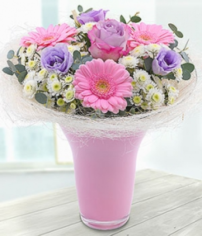Enchanted - A delicate lilac and pink vase arrangement. Roses and Germinis married with lilac Lisanthus blooms are neatly nestled in amongst white Spray Chrysanthemums.