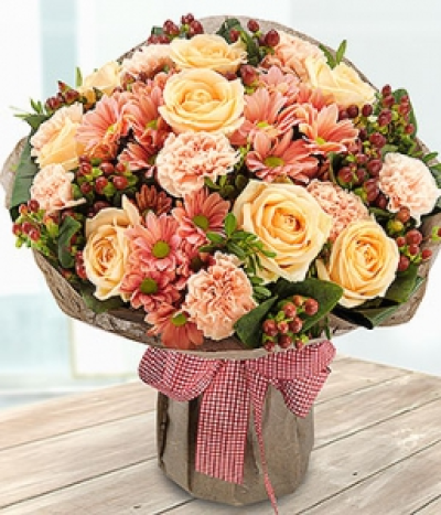 Caramel Cup - An incredibly attractive caramel coloured aqua pack bouquet. Pretty peach Roses, Spray Chrysanthemums and Carnations with a generous helping of red Hypericum Berries.