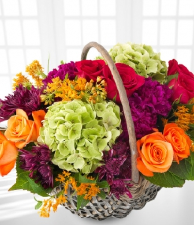 Pumpkin Patch - Orange roses and red roses take centrestage in this colourful wicker basket arrangement, accompanied by violet carnations, chrysanthemums and green hydrangea, alongside orange asclepias.