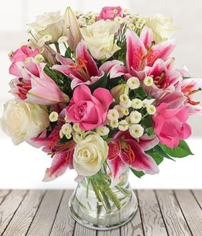 Mayflower - Pink lilies are presented with pink roses and white roses, topped with button tanacetum in this beautiful bouquet.