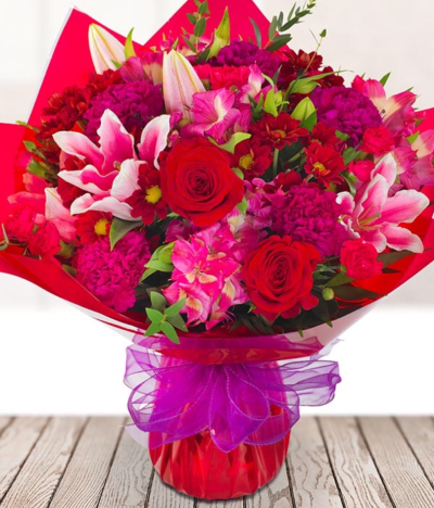 Lucky You - A romantic bouquet full of rich red and deep pink tones. This simply stunning hand-tied bouquet is presented beautifully to convey the right message to your loved one.